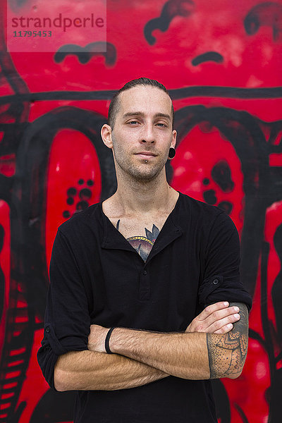 Porträt eines Mannes vor einer Graffiti-Wand