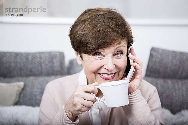 Porträt einer älteren Frau mit Smartphone  Kaffee trinken