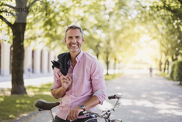 Porträt eines lächelnden Mannes mit Fahrrad im Park