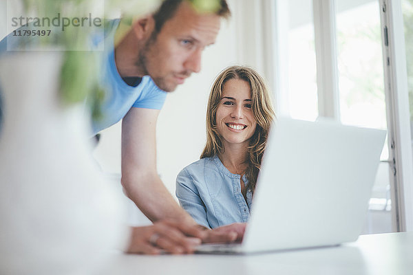 Lächelnde junge Frau und Mann mit Laptop zu Hause