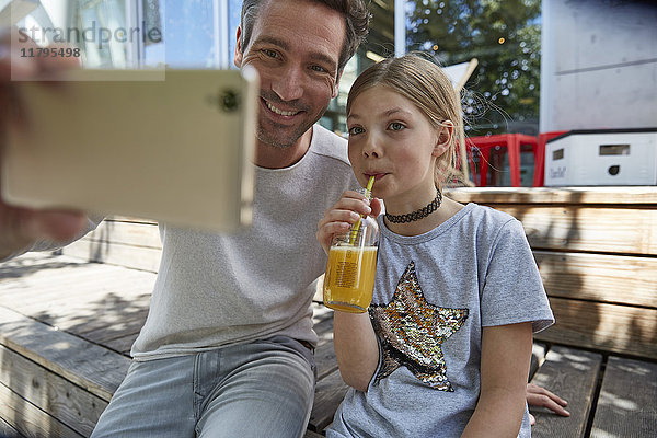 Glücklicher Vater und Tochter  die einen Selfie in einem Outdoor-Café nehmen.