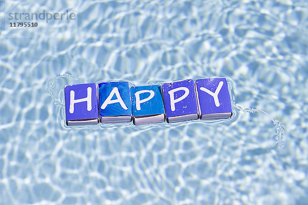 Buchstaben auf Streichholzschachteln  die das Wort Glücklich auf dem Wasser bilden.