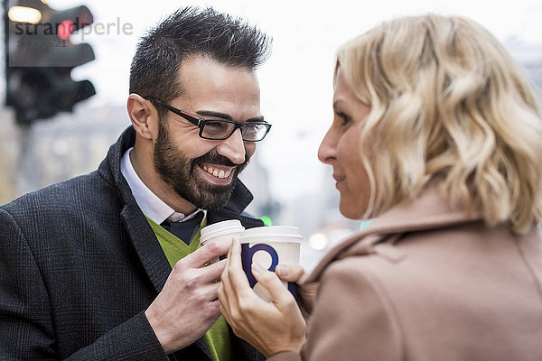 Lächelnder Geschäftsmann und Geschäftsfrau mit Kaffee zum Mitnehmen in der Stadt