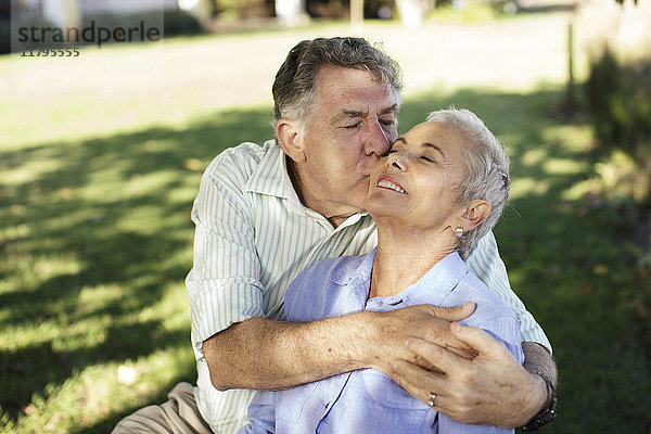 Senior Mann küsst seine Frau im Garten