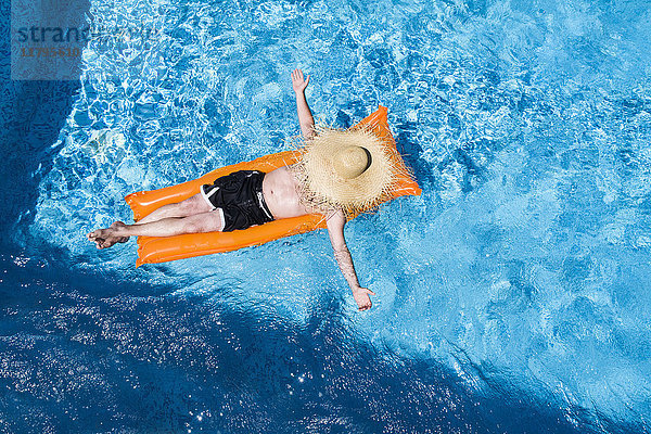 Mann entspannt auf orangefarbenem Luftmatratzenbett im Schwimmbad