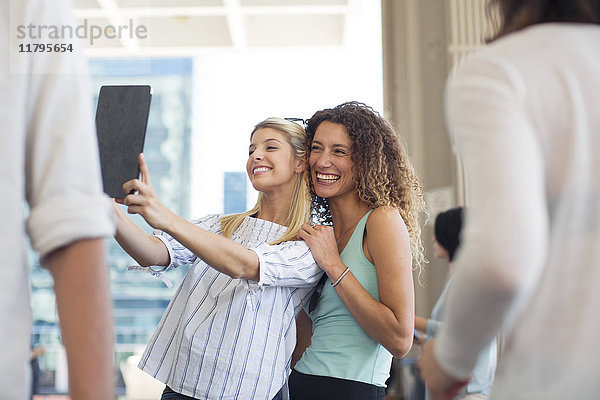 Zwei glückliche Frauen nehmen einen Selfie mit Tablette auf dem Stadtplatz.