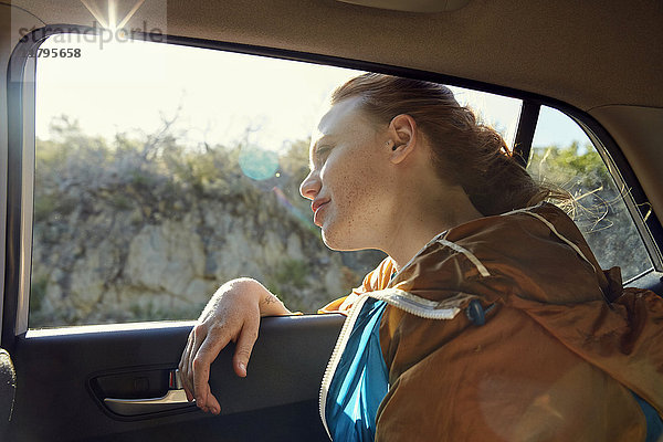 Junge Frau im Auto mit Blick aus dem Fenster