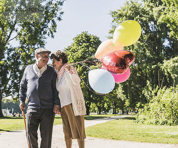 Glückliches Seniorenpaar mit Luftballons im Park