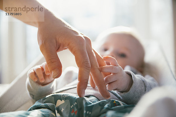 Baby berührt die Hand der Frau