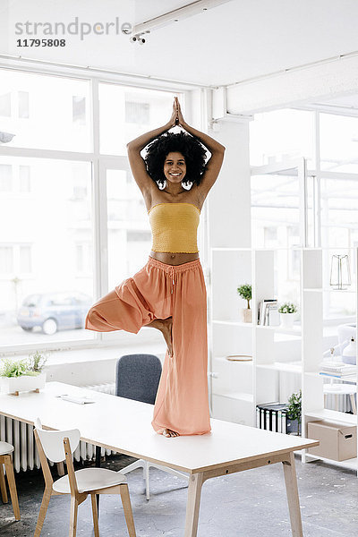Junge Frau beim Yoga auf dem Schreibtisch