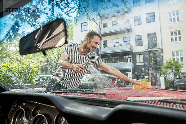 Lächelnder reifer Mann wäscht sein Auto