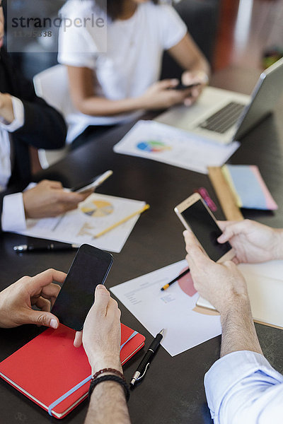 Geschäftsleute  die Mobiltelefone während eines Meetings im Büro benutzen