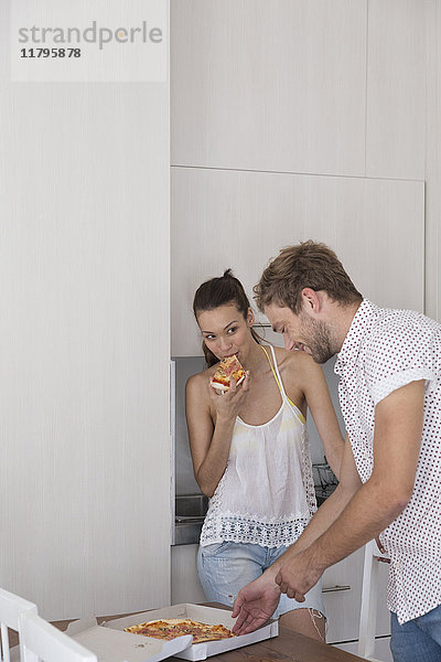 Junges Paar beim Pizzaessen in der Küche
