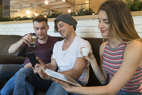 Drei Freunde mit Tablette und Handy in einem Cafe