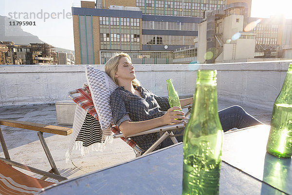 Junge Frau entspannt sich auf ihrer Terrasse