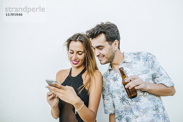 Junges Paar mit Bier und Handy im Freien