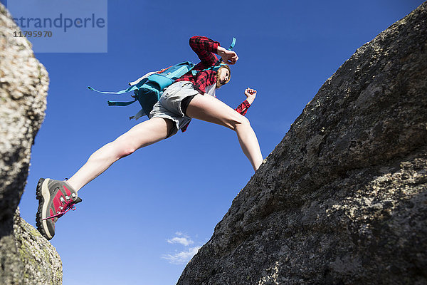 Spanien  Madrid  junge Frau  die während eines Trekkingtages zwischen Felsen springt.