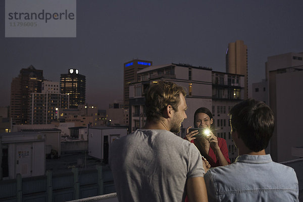 Junge Frau fotografiert Freunde auf einer Dachparty