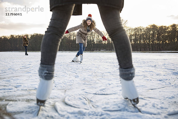 Frau beim Eislaufen auf dem zugefrorenen See mit Freunden