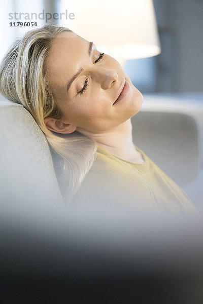 Porträt einer blonden Frau mit geschlossenen Augen auf der Couch