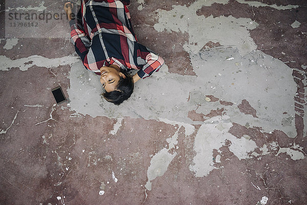 Frau auf gerissenem Boden liegend mit Handy