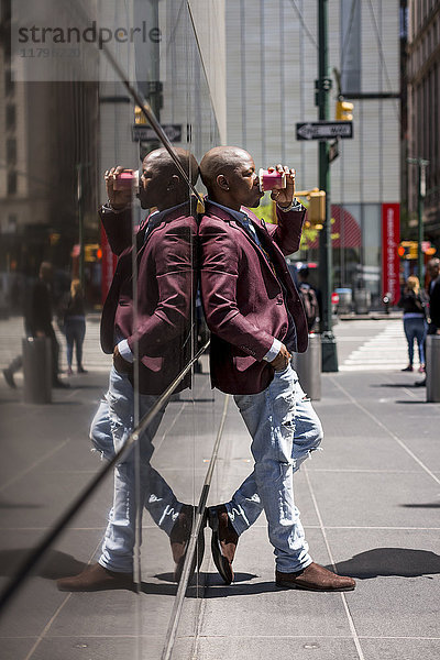 USA  New York City  Manhattan  stilvoller Geschäftsmann mit Kaffee zum Anlehnen an Glasfassade