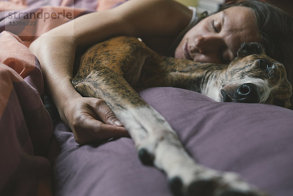 Frau im Bett liegend mit ihrem Hund