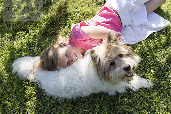 Mädchen mit Hund auf der Wiese liegend