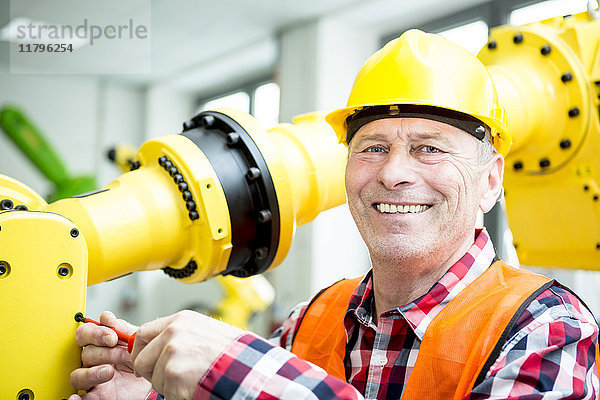 Porträt eines lächelnden Technikers am Industrieroboter