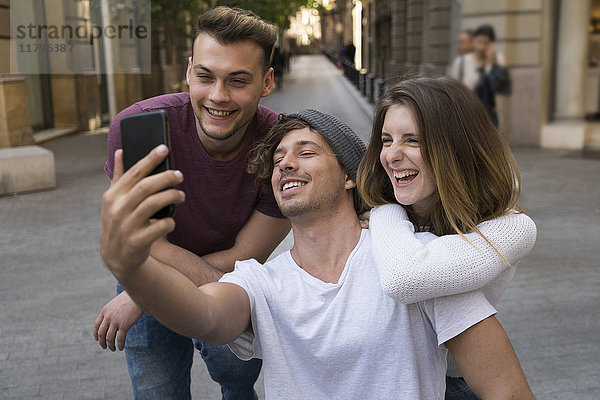 Drei glückliche Freunde  die einen Handy-Selfie in der Stadt mitnehmen.