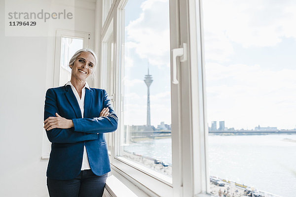 Porträt einer selbstbewussten Geschäftsfrau am Fenster im Waterfront Office