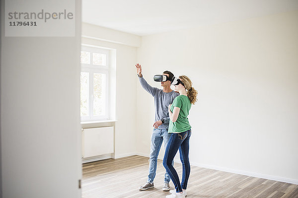 Junges Paar in leerer Wohnung mit VR-Brille