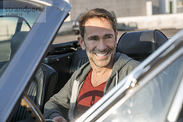 Porträt eines lächelnden reifen Mannes in seinem Sportwagen