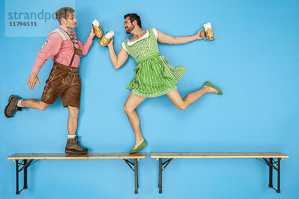 Schwules Paar auf dem Oktoberfest tanzt auf Bierbänken