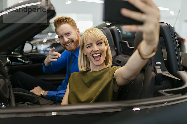 Paar  das sich selbst nimmt  sitzt im Cabrio im Autohaus