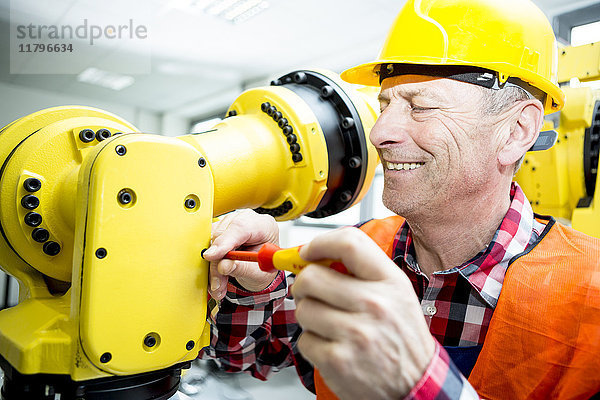 Lächelnder Techniker bei der Arbeit am Industrieroboter