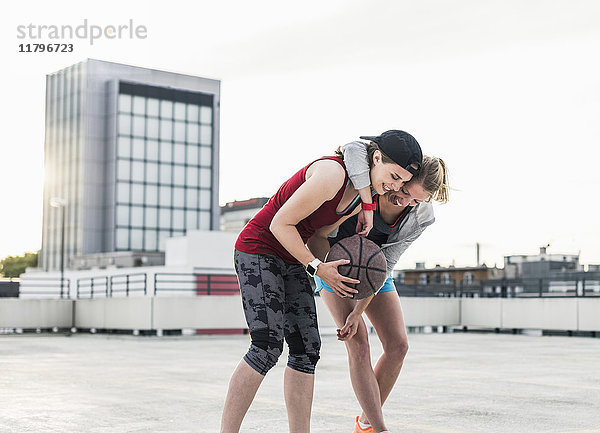 Zwei glückliche Frauen mit Basketball auf Parkebene in der Stadt