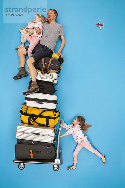 Mädchen schiebt Gepäckwagen mit Eltern auf dem Dach