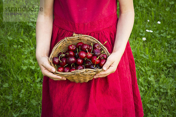 Kleines Mädchen in rotem Sommerkleid mit Kirschkorb  Teilansicht