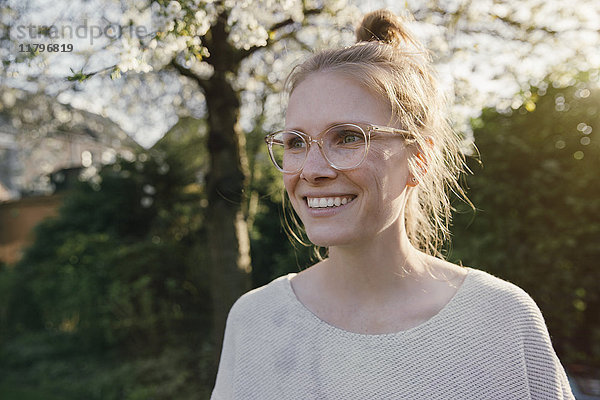 Porträt einer glücklichen blonden Frau im Garten