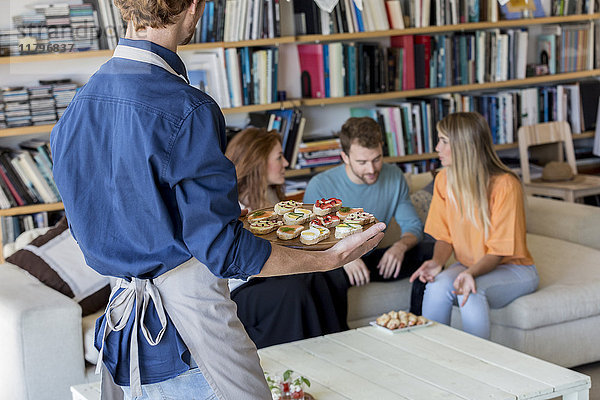 Mann serviert Aperitifs für Freunde