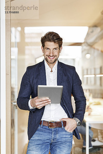 Porträt eines lächelnden Geschäftsmannes mit Tablette im Büro