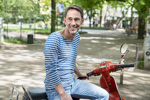 Porträt eines lächelnden reifen Mannes mit Motorroller