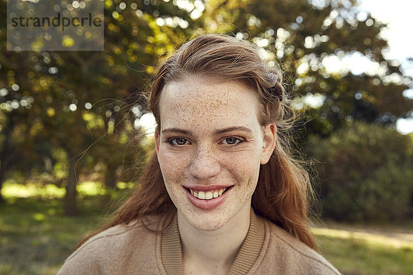 Porträt einer lächelnden rothaarigen jungen Frau mit Sommersprossen