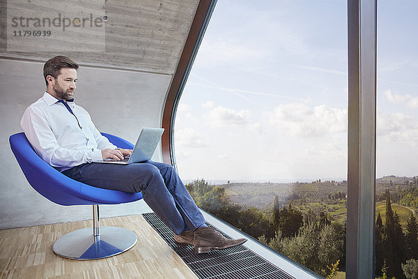 Geschäftsmann sitzend auf Stuhl im Dachgeschoss Büro mit Laptop