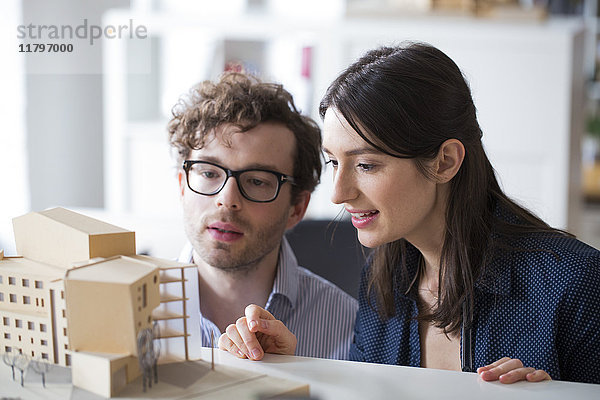 Mann und Frau diskutieren Architekturmodell im Büro
