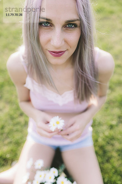 Porträt einer lächelnden jungen Frau mit Gänseblümchen