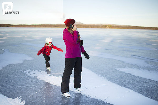 Mutter und Tochter beim Schlittschuhlaufen auf einem zugefrorenen See