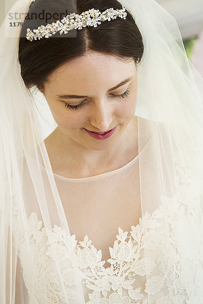 Eine Braut im Brautkleid  Diadem und Schleier  Kopf und Schultern. Ein modisches Kleid mit Spitzenmieder und Netzmieder und Ärmeln.