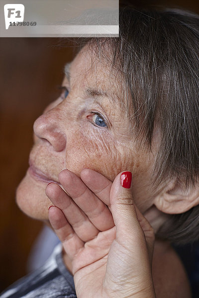 Hand einer Frau berührt das Gesicht einer älteren Frau